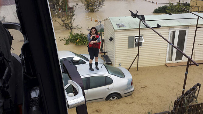 Una mujer espera ser rescatada en el techo de un vehículo.