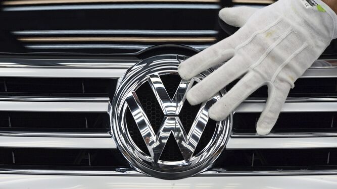Un operario coloca el logo de Volkswagen en un coche.