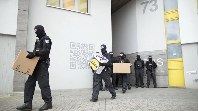 Varios policías enmascarados sacaban ayer documentación de un edificio de apartamentos en Berlín.