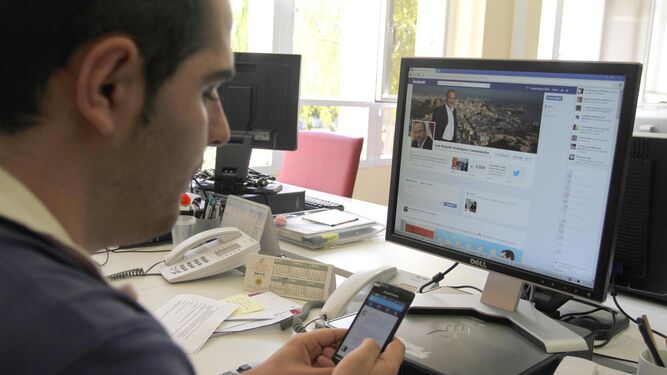Un joven consulta su muro de Facebook y su perfil de Twitter en el móvil.