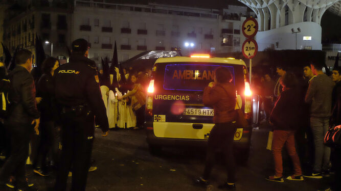 Una ambulancia pasa por el medio de la fila de nazarenos de los Gitanos en la plaza de la Encarnación.