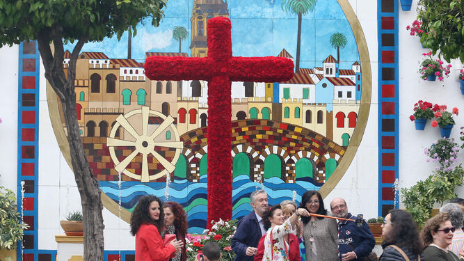 Varias personas se hacen fotografías delante del recinto de la cruz de la Asociación de Vecinos Cañero Nuevo.