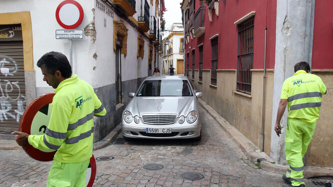 Operarios colocan nuevas señales mientras un coche sale de la calle Pedro López.