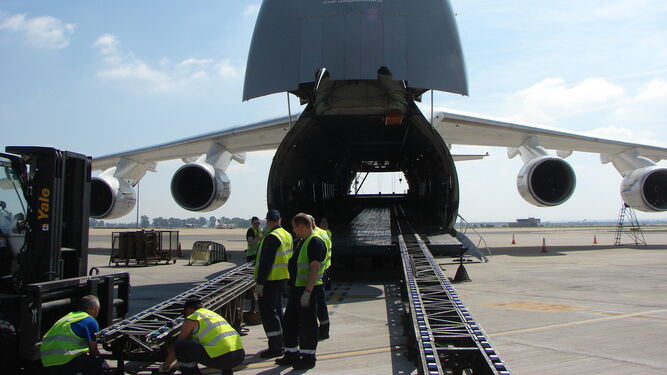 Operarios cargan el avión a través de una plataforma mecánica.