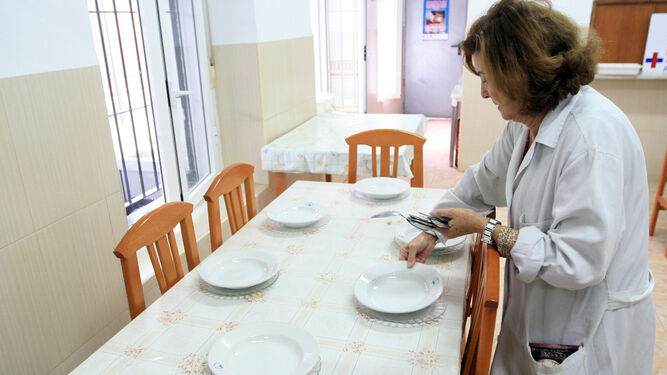 Una voluntaria pone una de las mesas del Comedor de Los Trinitarios.