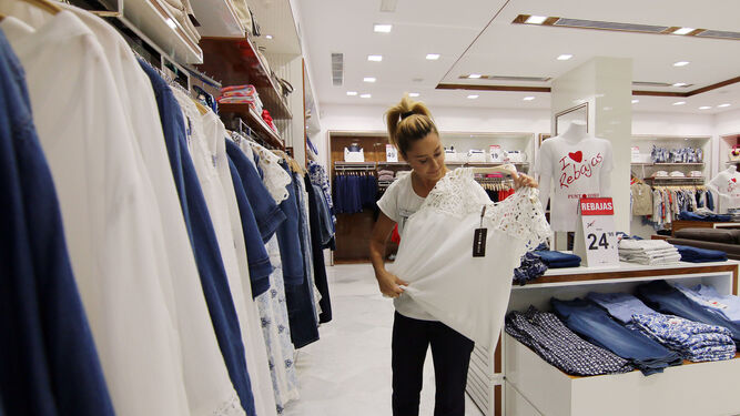 Una empleada de una tienda ordena una prenda de ropa.