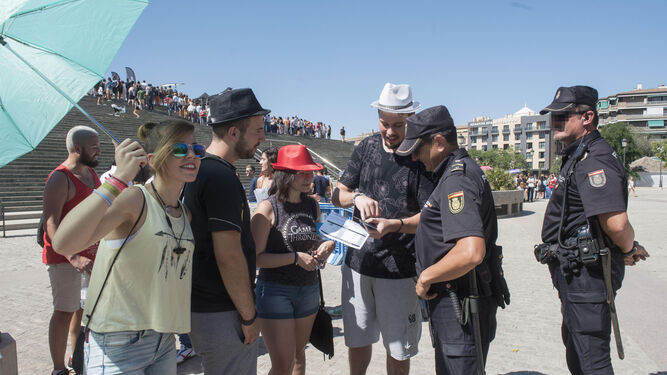 Una pareja de la Policía Nacional atiende a un grupo de turistas en Granada.