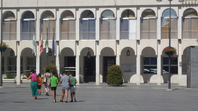 Varias personas pasan delante de la sede del Ayuntamiento lucentino.