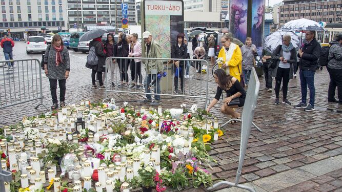 Varios finlandeses colocan velas y flores ayer en la Plaza del Mercado de Turku tras el ataque del pasado viernes.