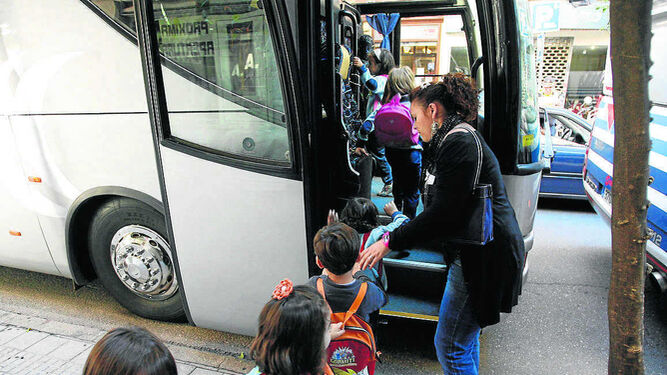 Varios pequeños se suben a un autobús escolar.