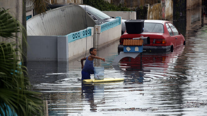 Un niño juega en una calle inundada tras el paso del huracán María.