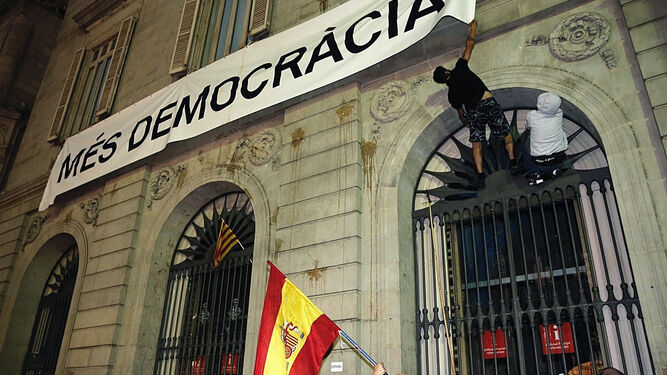 Un hombre intenta quitar ayer la pancarta del Ayuntamiento de Barcelona.