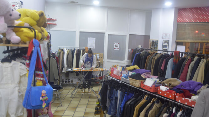 Una responsable de Sonrisa de Lunares plancha ropa en su tienda de la calle Compositor Ramón Medina.