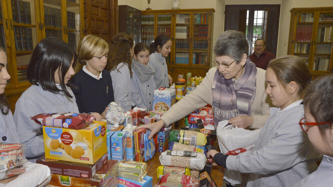 Alumnos del colegio Las Francesas ordenan los alimentos donados antes de su reparto.