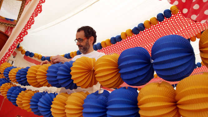 Un hombre prepara los farolillos de una caseta de la Feria del año pasado.
