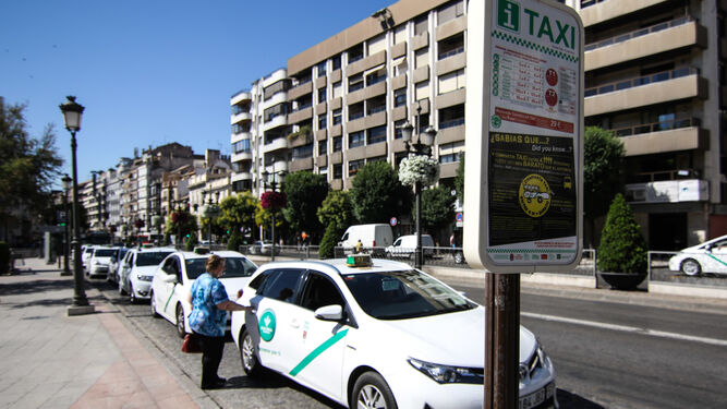 Una mujer sube a un taxi  en la Acera del Darro, en Granada.