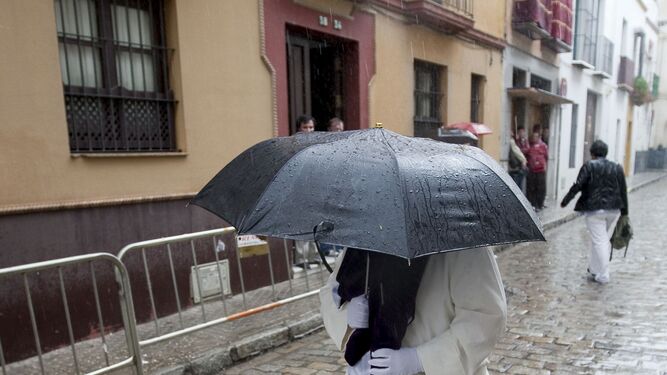 Un nazareno se protege de la lluvia.