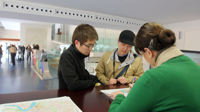 Una trabajadora atiende a dos turistas asiáticos en el Centro de Recepción de Visitantes (CRV).