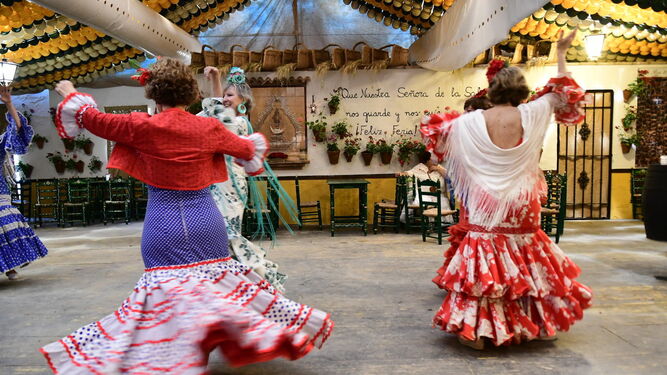 Varias mujeres bailan sevillanas en la caseta La Reja.