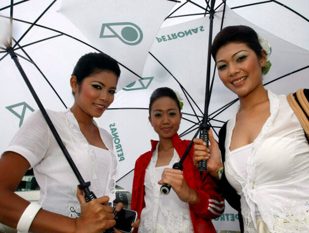 Varias azafatas se cubren con paraguas durante una tormenta antes de que d&eacute; comienzo el Gran Premio

Foto: Efe
