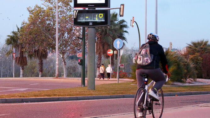 Un ciclista pasa junto a un termómetro con un grado bajo cero.