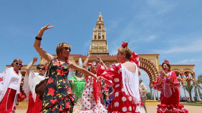 Varias mujeres bailan junto a la portada de la Feria.