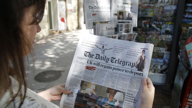 Una mujer lee el periódico británico The Daily Telegraph.