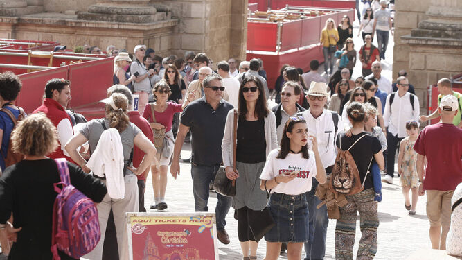 Un nutrido grupo de turistas pasea por la Puerta del Puente con las estructuras de la carrera oficial a los lados.
