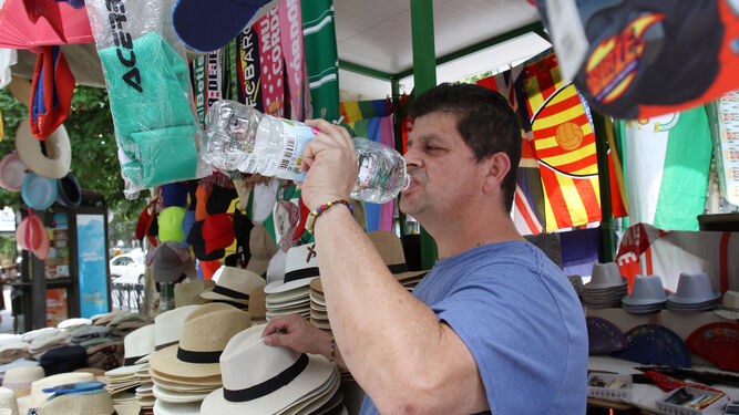 Un vendedor bebe agua en su puesto del centro de la ciudad.