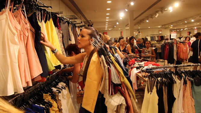 Una joven elige ropa en una tienda en las rebajas de verano de 2016.