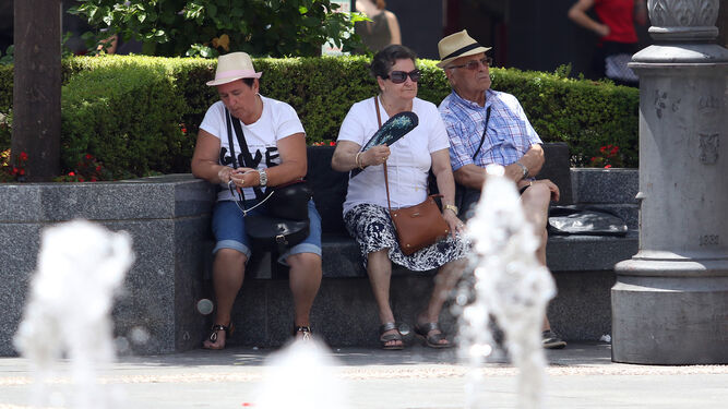Un grupo de personas mayores se refugia del calor en la Plaza de las Tendillas.