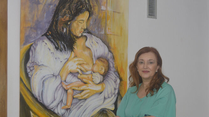 La jefa de Obstetricia y Ginecología del Reina Sofía, junto a un cuadro referente a la lactancia.