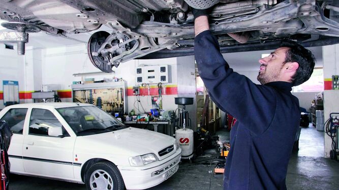 Un mecánico trabaja en un coche en un taller.