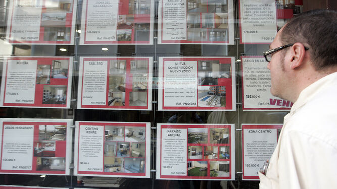 Un hombre mira un escaparate con anuncios de viviendas en alquiler.