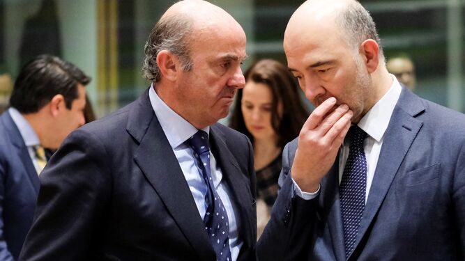 Luis de Guindos conversa, ayer, Pierre Moscovici, en Bruselas.
