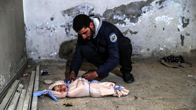 Un voluntario de Defensa Civil Siria escribe información en el cuerpo de un niño alcanzado por una bomba en Duma.