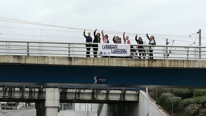 Integrantes de IU cuelgan una bandera por la huelga del 8 de marzo.