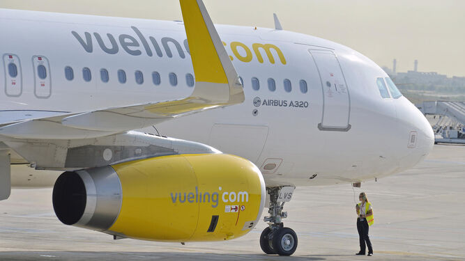 Una operadora junto a un avión de la compañía Vueling.