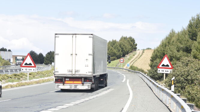 Un camión circula entre dos señales que advierten de irregularidades en el firme.