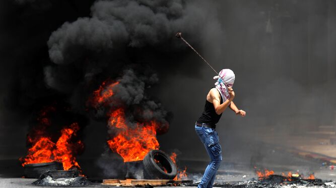 Un palestino arroja piedras contra las tropas israelíes durante un enfrentamiento en la ciudad cisjordana de Hebrón.