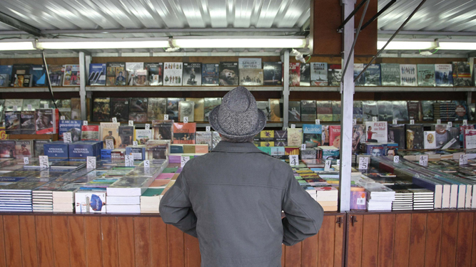 Un lector escruta las novedades literarias en una caseta de la Feria del Libro de Algeciras.
