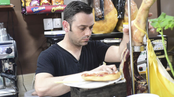 Pedro González prepara una tostada con jamón serrano al corte, el desayuno predilecto de sus clientes.