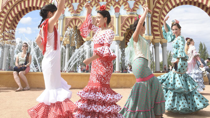 Unas jóvenes bailan sevillanas en la entrada de El Arenal.
