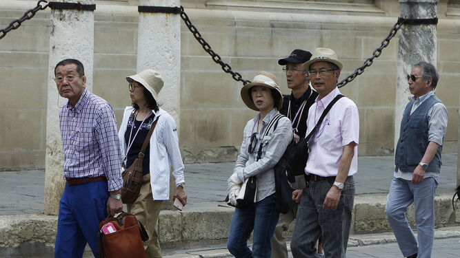 Varios turistas japoneses pasean por los alrededores de la Catedral de Sevilla.