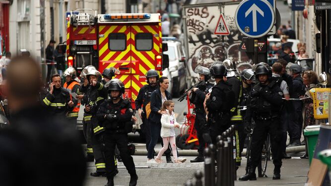 Una mujer y una niña, en el centro, son evacuadas por las fuerzas policiales durante la toma de rehenes ayer en la calle des Petites Ecuries de París.