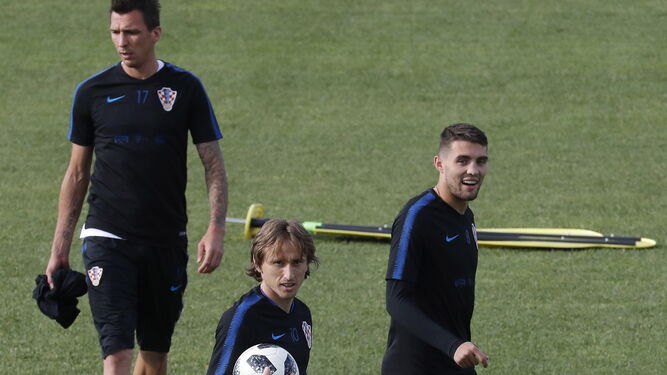 Modric camina con un balón en las manos con Mandzukic detrás.
