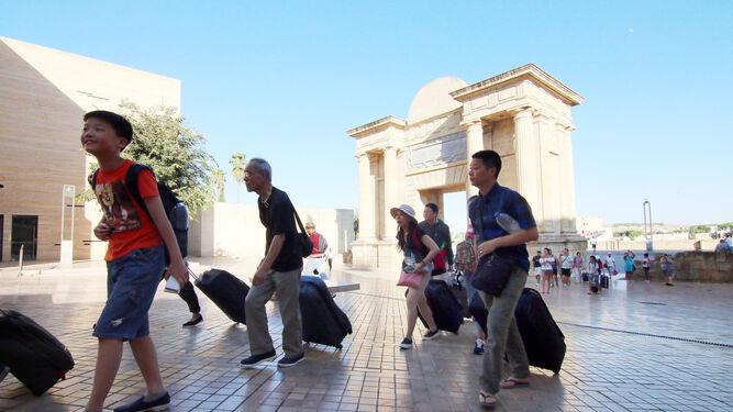 Un grupo de turistas camina con maletas junto a la Puerta del Puente.