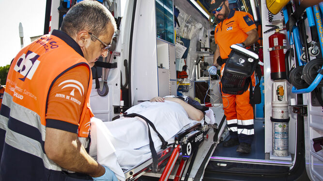 Un técnico sanitario introduce a una enferma en una ambulancia del 061.