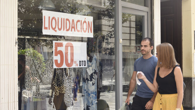 Dos jóvenes pasan delante de una tienda en el Centro de Córdoba.