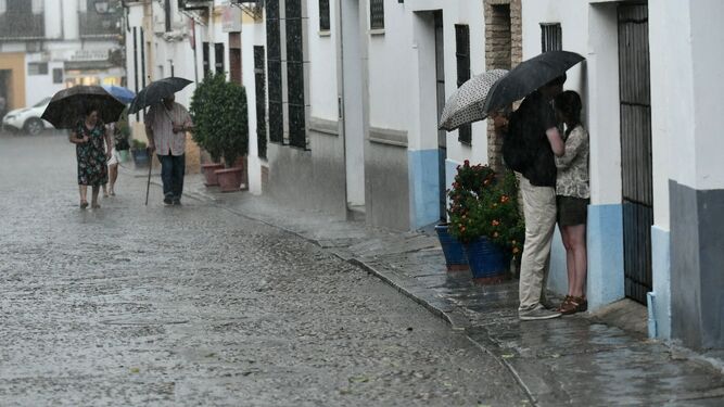 Una pareja se resguarda de la tormenta bajo un paraguas.